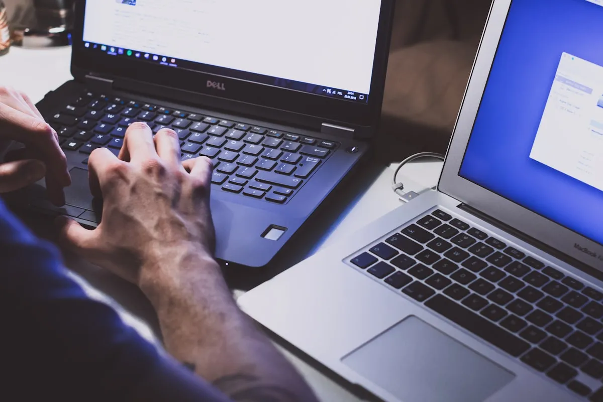 Développement d'un site web : mains sur le clavier entre deux ordinateurs