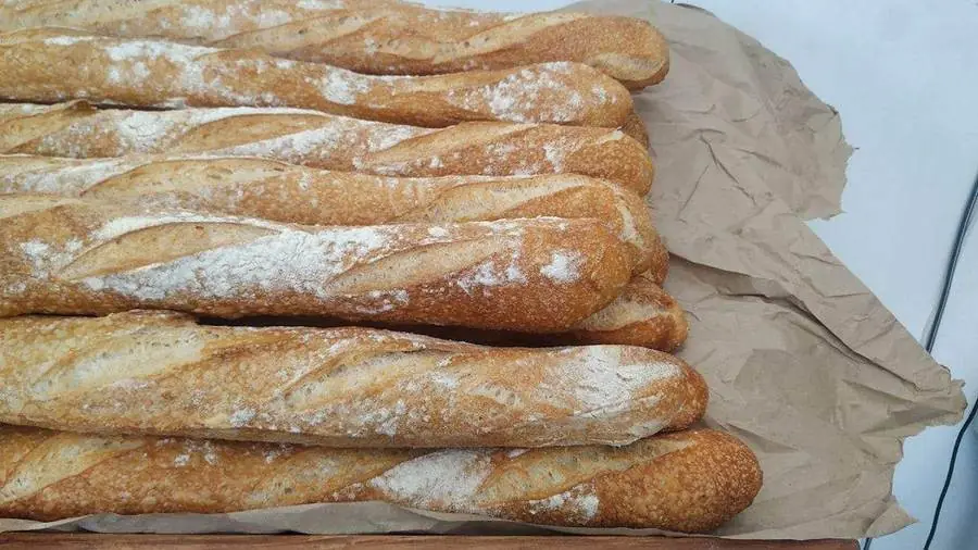 Baguettes de tradition dorées et farinées posées sur du papier kraft