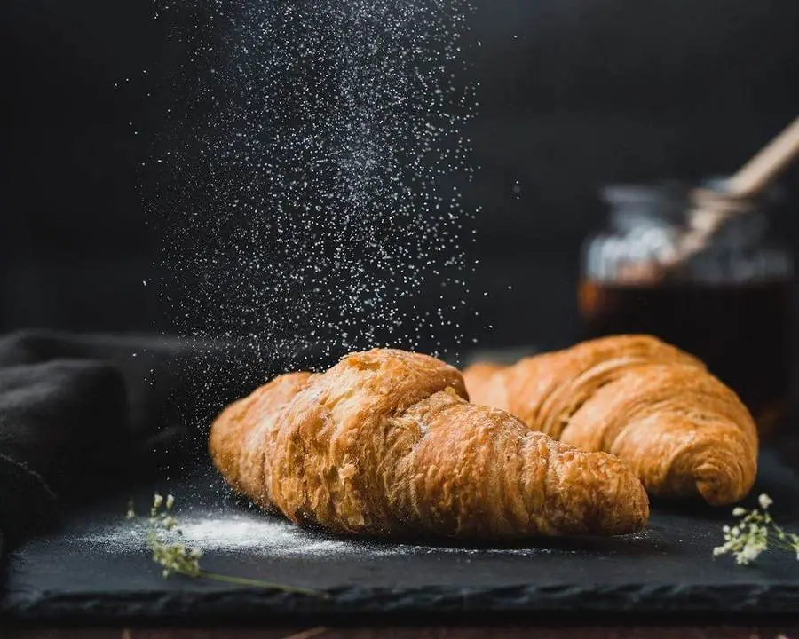 Croissant pur beurre saupoudré de farine sur fond sombre
