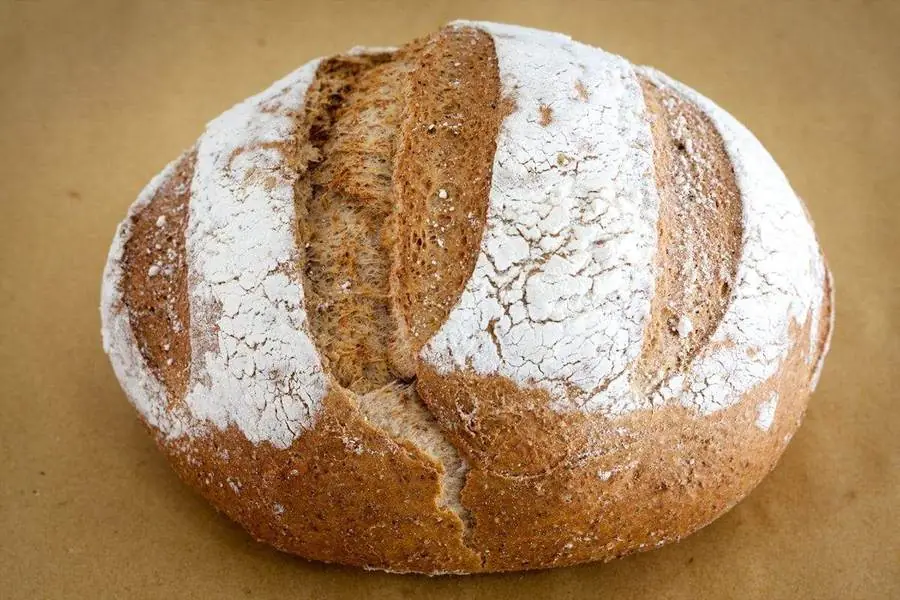 Grosse boule de pain de campagne au levain, scarifiée et couverte de farine