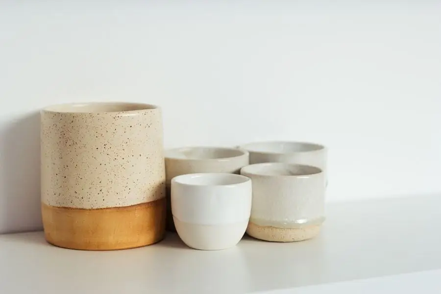 Tasses en grès moucheté beige et blanc alignées à côté d’un vase assorti