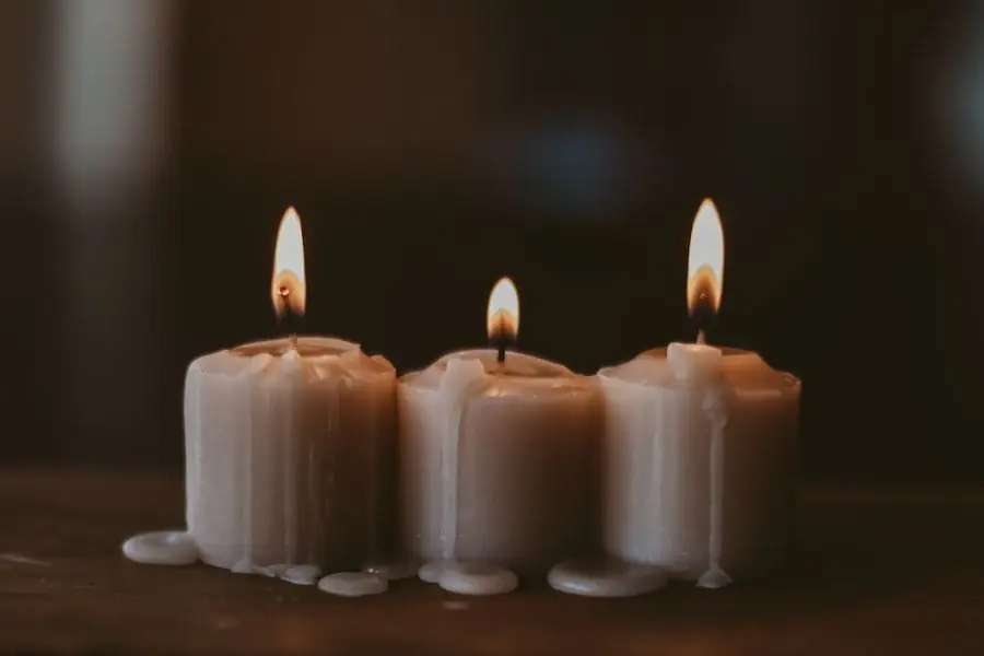 Trio de bougies coulées à la main, flammes allumées sur une table en bois sombre